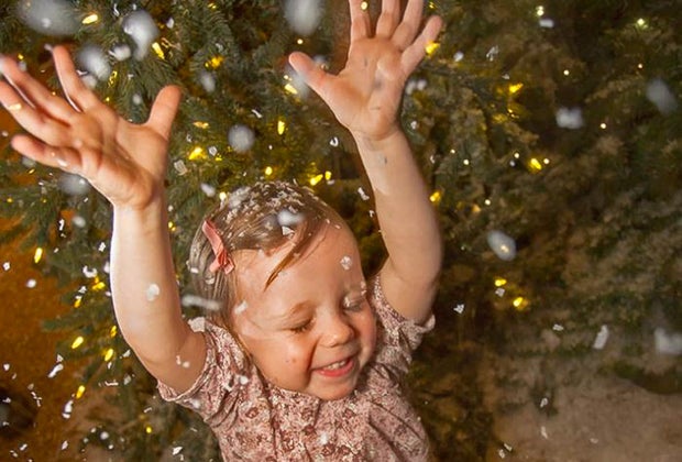 Photo of child in falling snow with Christmas lights.