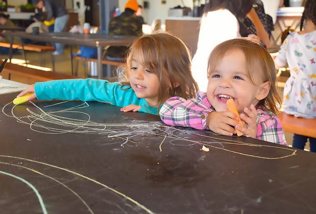 Two girls laughing and drawing at the Social Pay Haus Play Spaces on Long Island Open Now