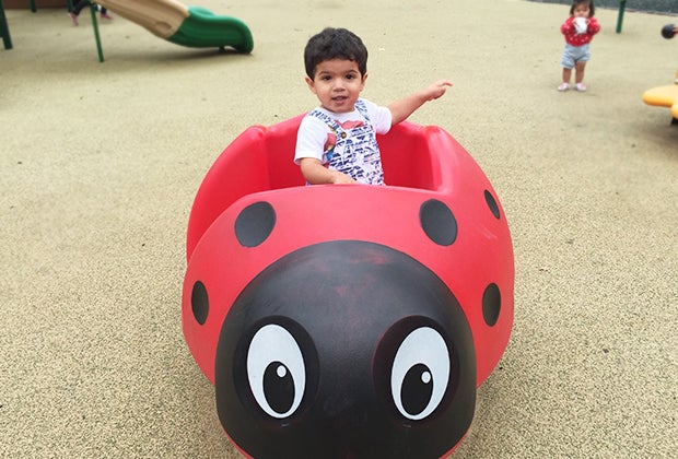 toddler in a ladybug structure on playground