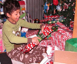 Jody Mercier photo of little boy opening Christmas gift in delight before Christmas tree