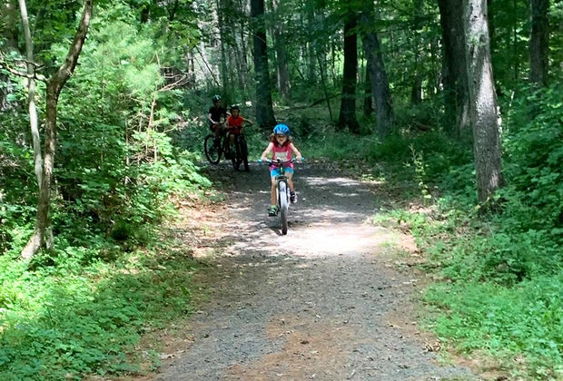 Camping near NYC: Child riding bike on a path through the woods at Dingmans Campground