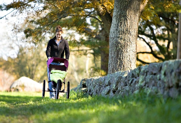 Photo of parent pushing a stroller on a hike in a field