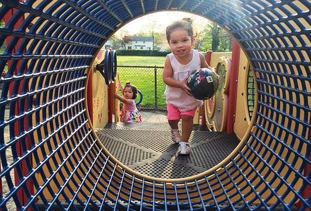 toddler runs through a tunnel at a playground