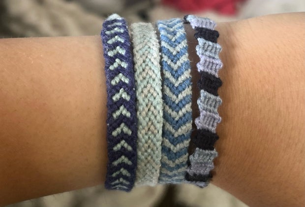 3 friendship bracelets on a kids wrist, all in different cool patterns