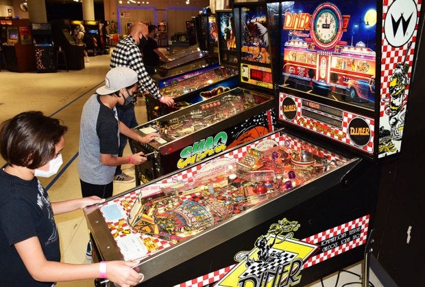 Kids playing on pinball machines at an arcade