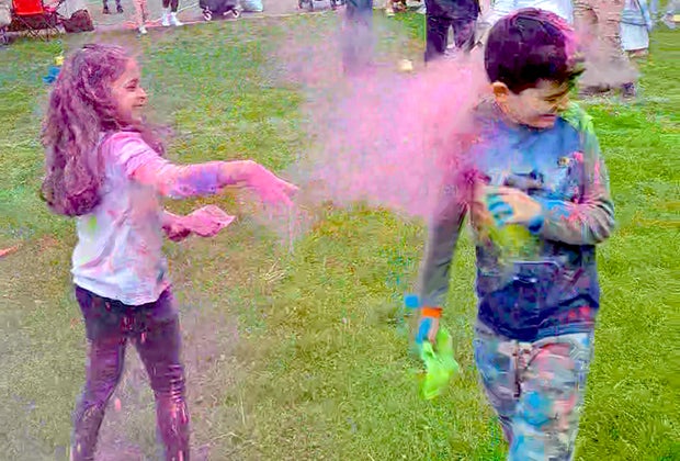 kids tossing bright colors on each other in a field of grass