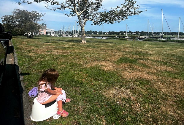 little girl using a portable potty in the park