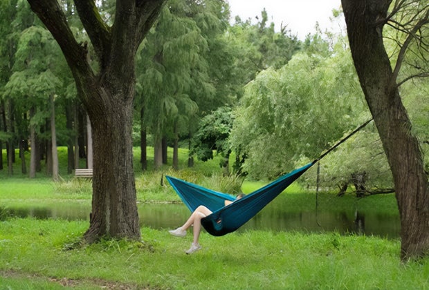 girl relaxing in a portable hammock by a stream for Hammock Day 
