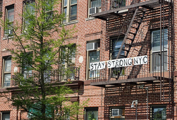 Stay Strong NYC sign hangs from a Harlem fire escape