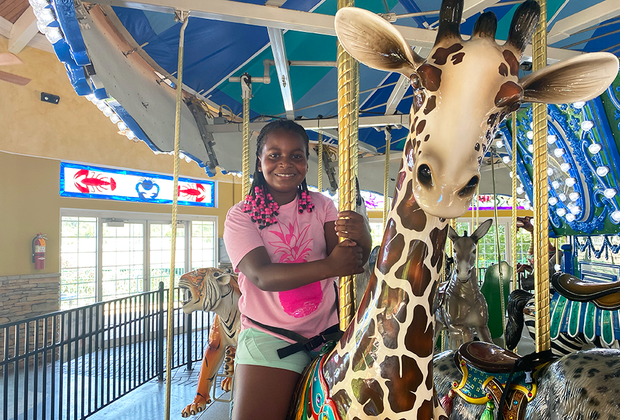 girl rides the carousel at the Turtle Back Zoo