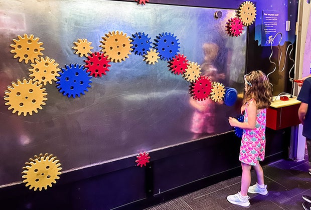 girl playing on interlocking gear wall