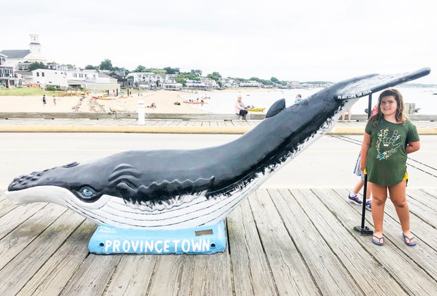 Photo of young woman with whale statue on Cape Cod.