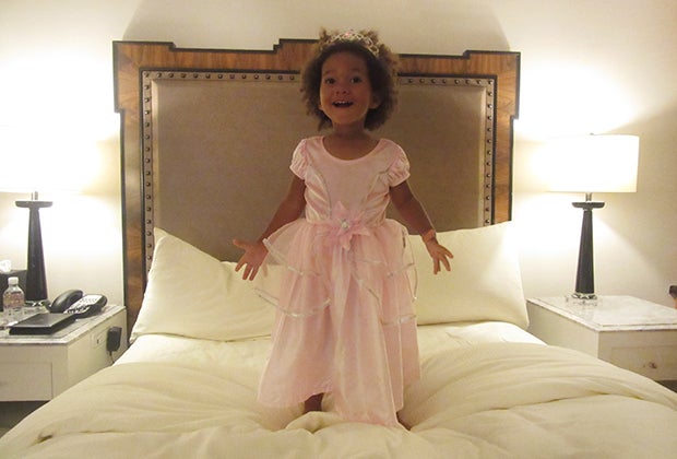 Little girl in princess costume jumping on bed Lotte hotel