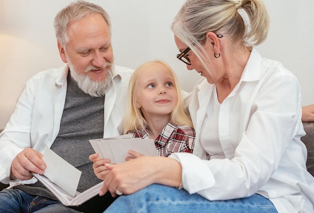 child sitting with grandparents looking through photos 101 Questions To Ask Grandparents About Their Lives