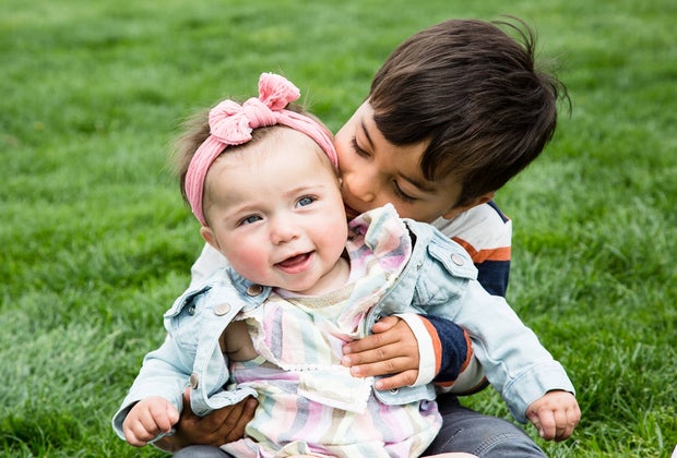 Big brother holding and kissing baby sister