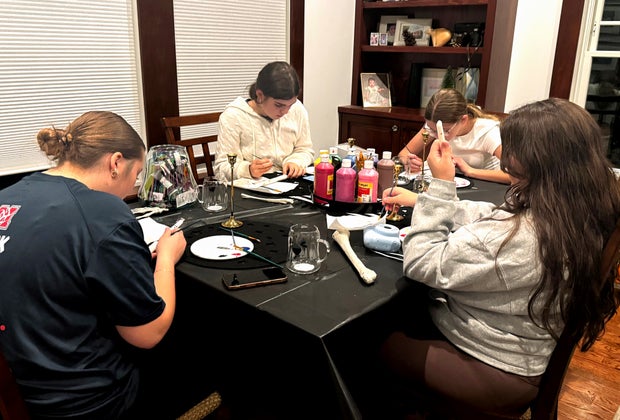 4 teen girls sit around a table, painting crafts