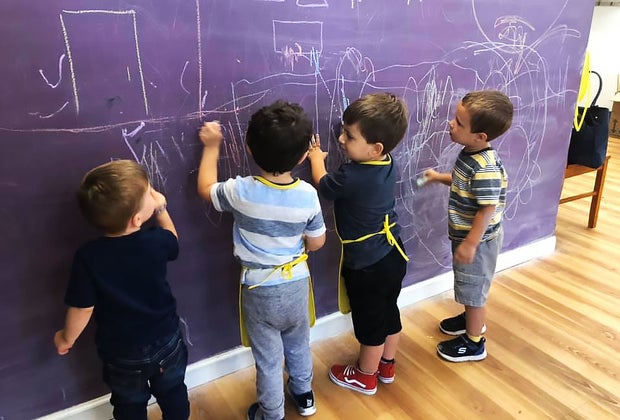 little kids draw on a chalk wall
