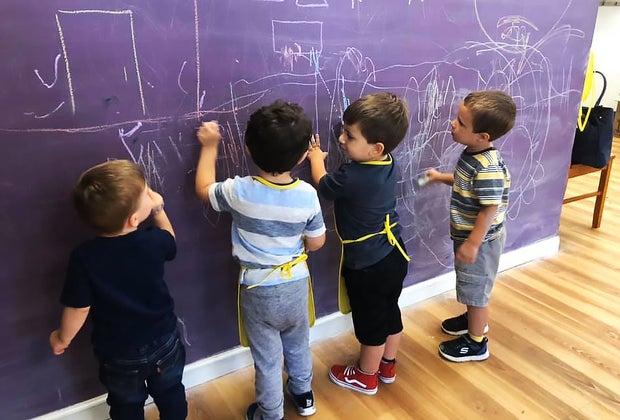 little kids draw on a chalk wall