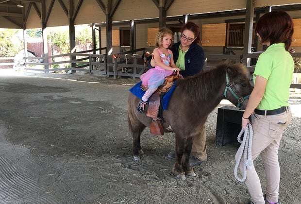 girl riding a pony with a guide at Turtle Back Zoo