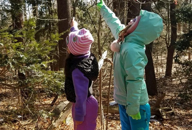 Two girls in the woods pointing at wildlife Greenburgh Nature Center Westchester winter walks