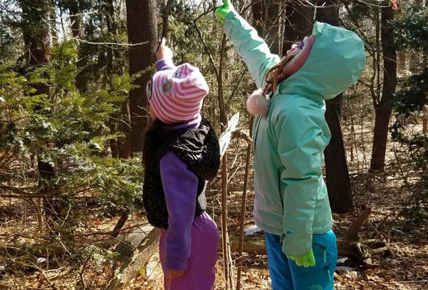 Two girls in the woods pointing at wildlife Greenburgh Nature Center Westchester winter walks